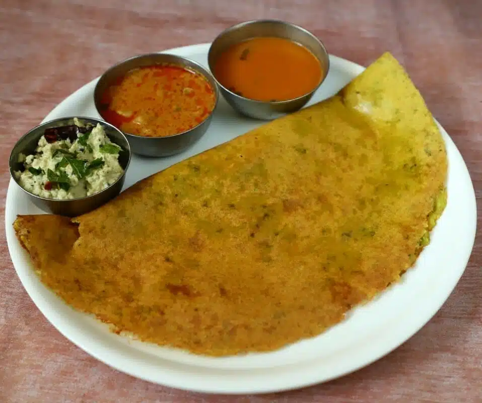 Close-up of crispy pesarattu cooking on a skillet 