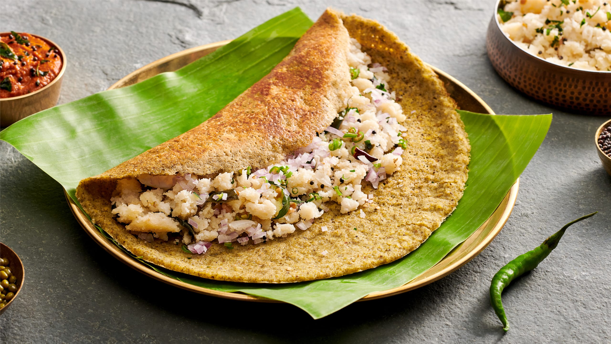 Pesarattu crepe served with chutney on a white plate