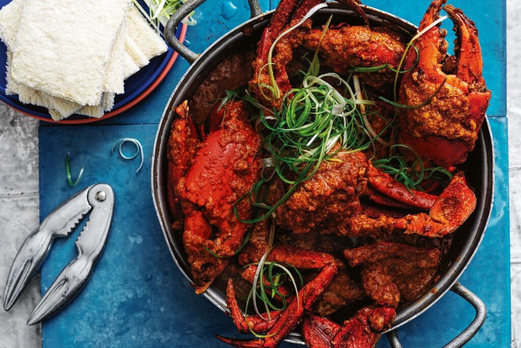 A plate of Singaporean Chilli Crab Delight in a rich, spicy tomato-based sauce, served with crispy mantou buns